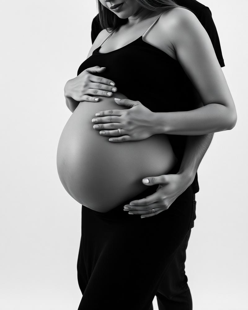 Casal em ensaio gestante em preto e branco com as mãos na barriga
